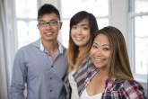 Group portrait of three Asian friends relaxing at home.