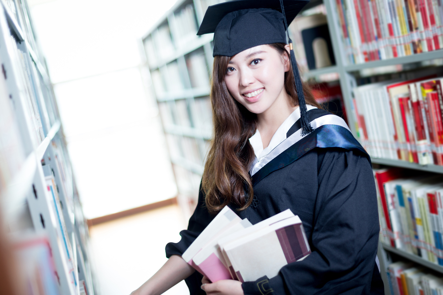 Asian beautiful female student holding book in library