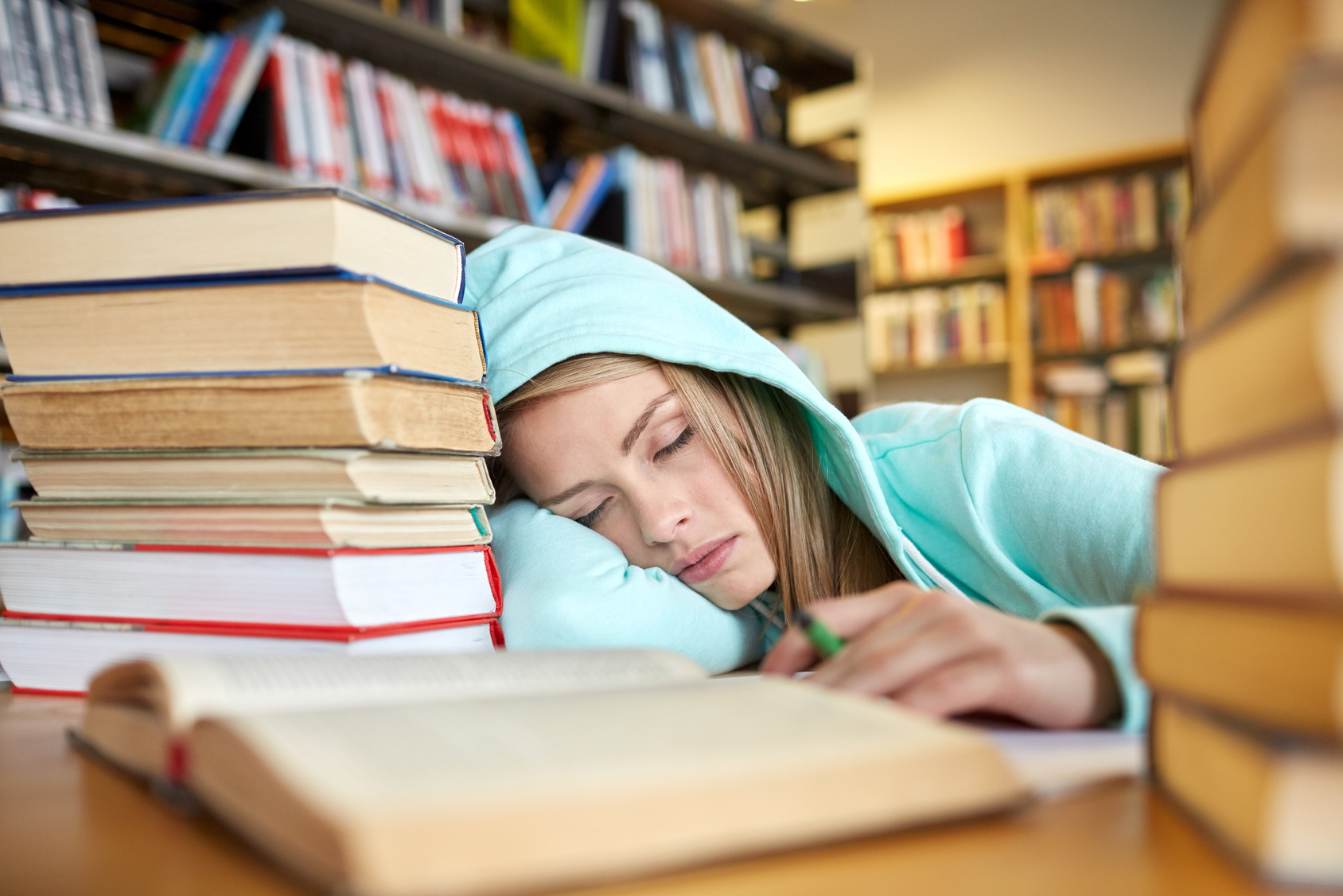 people, education, session, exams and school concept - tired student girl or young woman with books sleeping in library