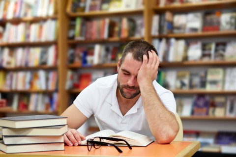 Tired man in a polo shirt sleeping in the library